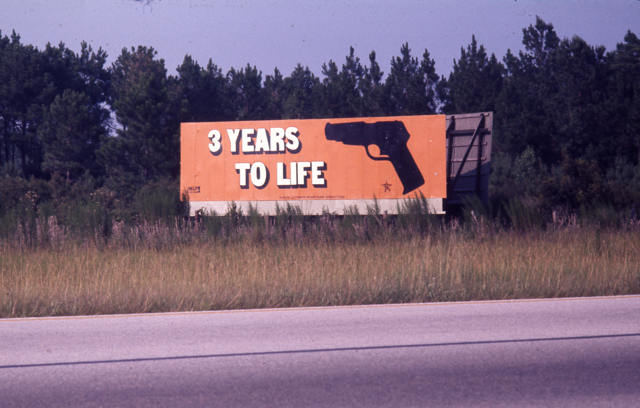 Slide 2: A picture of a billboard advertising '3 Years to Life' next to a drawing of a gun